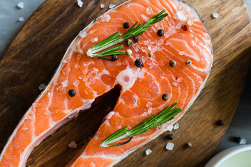 Fresh raw salmon fish steak with spices on dark stone background. Creative layout made of fish, top view, flat lay, mockup, overhead. Healthy food concept