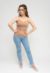 Photo full-length portrait of a pretty brunette woman girl with long beautiful curly hair on a white background in a t-shirt and blue jeans. Talking while standing in front of the camera.