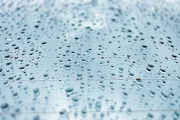 In selective focus rain droplets on a car mirror with blue tone for background texture