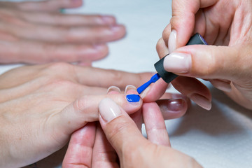 Obraz na płótnie Canvas Beautiful manicure process. Nail polish being applied to hand, polish is a blue color. close up