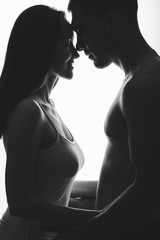 Romantic silhouette of a young couple hugging face to face, nose to nose, forehead to forehead.