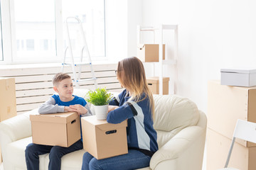 Cute single mom and little boy son sort boxes with things after the move. The concept of housewarming mortgage and the joy of new housing.