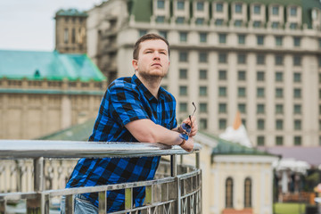 Young man with seriously mood look at the view of city, plump people concept, one in big city life. Image of guy at downtown 