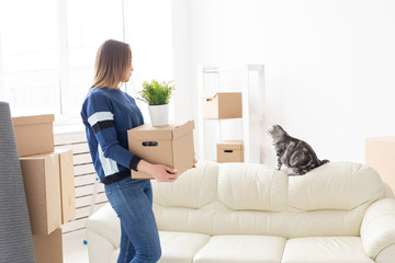 Charming young single woman holds a box with things while moving while standing in a new apartment...