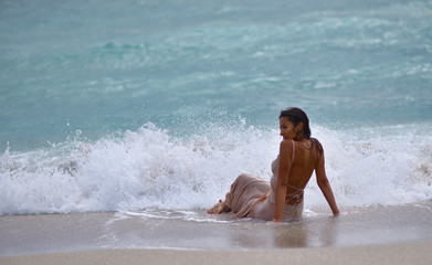Fototapeta na wymiar girl in a dress on the sand by the sea