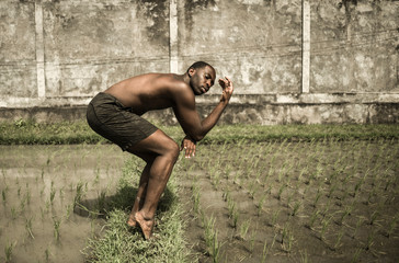 young attractive contemporary ballet dancer and choreographer , a black African American man dancing and posing on tropical rice field background