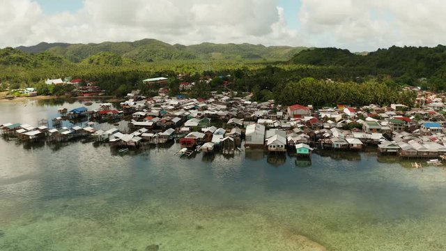Fishing village with boats and slums with wooden houses, aerial drone. Dapa, Siargao, Philippines.