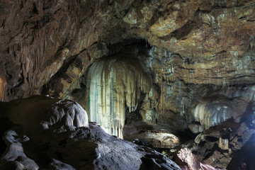 stalactites and stalagmites in the cave are illuminated by artificial light
