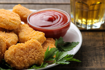 Chicken nuggets with red sauce and beer on a brown wooden table. fast food. close-up