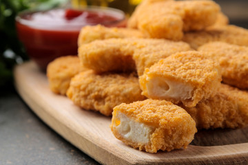 Chicken nuggets with red sauce, ketchup on a wooden board on a brown table. fast food.