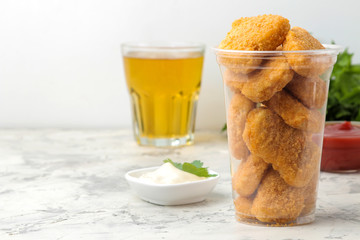 Chicken nuggets with red sauce, ketchup in a disposable glass on a light concrete table. fast food.