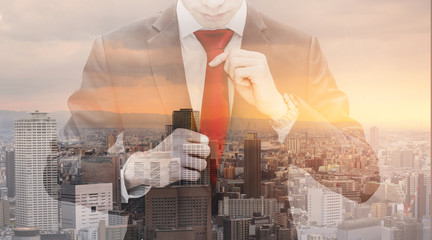 Double exposure businessman tying red necktie and cityscape in sunset