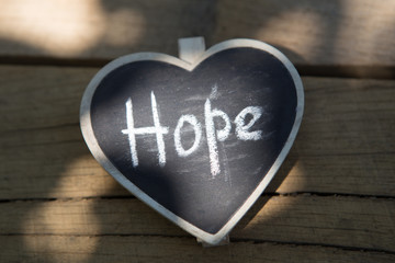 Hope - inscription on the heart, sharing hope concept, wooden background