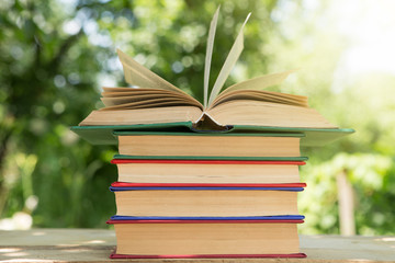 Studying in summer concept. Open book on a wooden table in a garden, sunny summer day