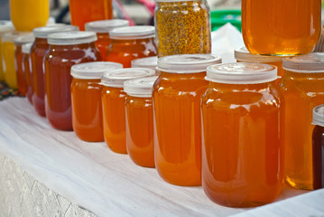 Lots of assorted honey on the table. Jars of sweets are sold at the fair.
