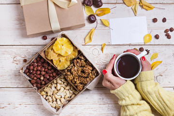 A box of nuts and dried fruits on old wooden background. hazelnut, cashew, dried daddy, dried pineapple. A gift on the day of the anniversary. Nuts as a gift.