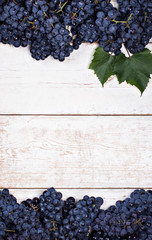 Blue grapes on white old boards. Background with grapes, Top view, closeup. Place for your text.
