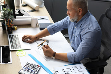 Senior businessman with a stylish short beard working on laptop computer at his office desk.