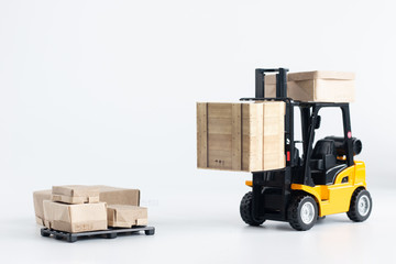 Miniature forklift truck model loading cardboard box isolated on white background with copy space for text message