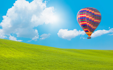 Hot air balloon flying over spectacular green grass field