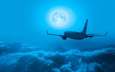 Fototapeta na wymiar Commerical passenger airplane in the storm clouds - Night sky with moon in the clouds 