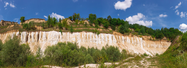 Beautiful sunny summer panorama of forests and blue sky. Horizontal color photography.