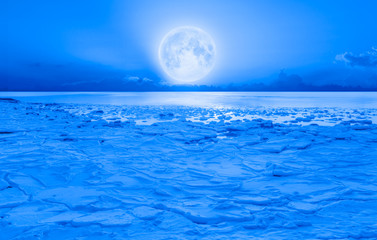 Night sky with moon in the clouds - Ice on the ocean shore at night "Elements of this image furnished by NASA"