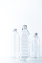 Plastic bottles in various shapes and sizes on white table and background
