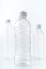 Plastic bottles in various shapes and sizes on white table and background