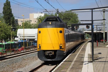 Yellow blue intercity train at the station of the city Gouda heading to Utrecht