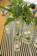 beautiful elegant wedding table decorated with glass candlesticks, glasses, plates, a bouquet of greens with a tablecloth