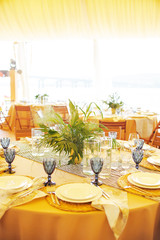 beautiful elegant wedding table decorated with glass candlesticks, glasses, plates, a bouquet of greens with a tablecloth