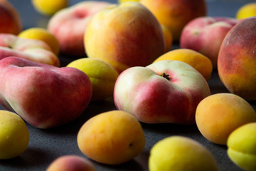 Apricots and peaches on dark texture surface. Close up of fresh summer fruits.