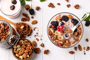 Granola crispy honey muesli with natural yogurt, fresh berries, chocolate and nuts in a bowl against a light background, healthy food, horizontal orientation, top view