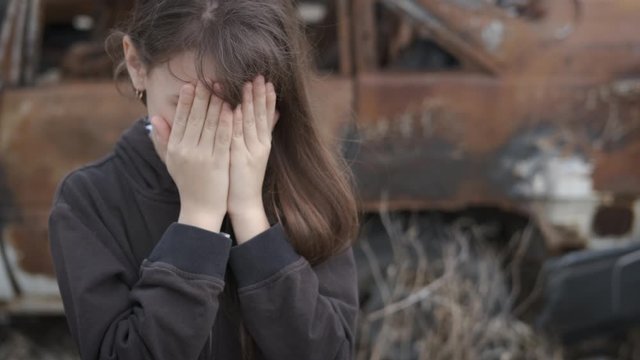 The homeless child is crying. A little orphan girl covered her face in pain in a landfill. A cry of despair.