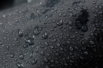 dark gray waterproof hydrophobic cloth closeup with water drops selective focus background