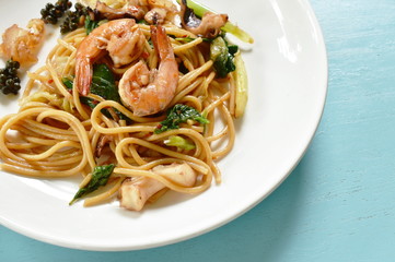 spicy stir fried spaghetti seafood with pepper and basil leaf on plate