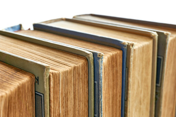 Old books in a row. Monochrome coloured weathered, aged, stained and torn antique books isolated on white. Closeup shot with selective focus.