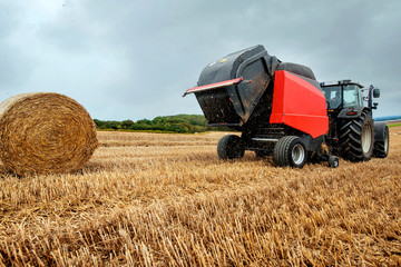 farmer in fields making straw bales
