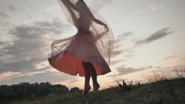 The girl in the dress swirls magically at sunset.