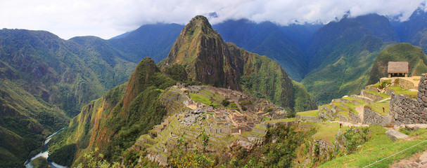 Great panoramic vew of Machu Picchu, Peru. Lost city shot from above. Mountains around. Day light. Clouds. Sunshine. Panorama