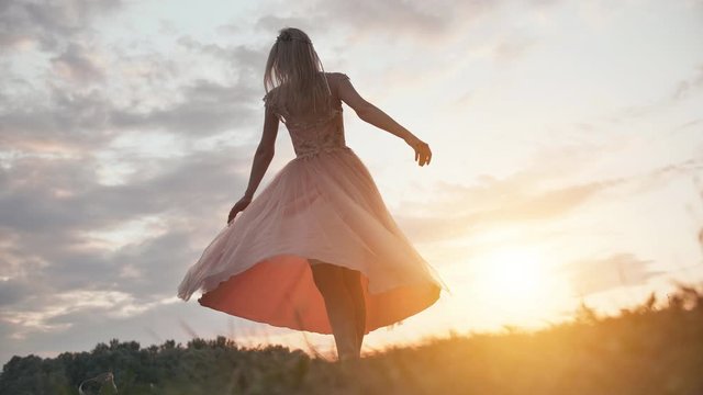 The girl in the dress swirls magically at sunset.