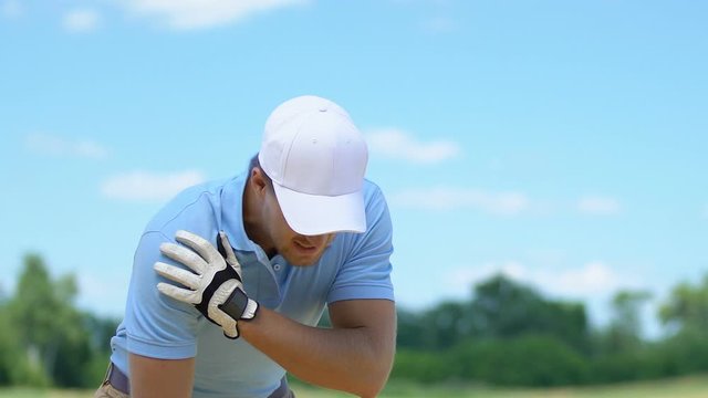 Male golf player hitting drive and spraining his shoulder, professional trauma