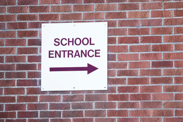 Fototapeta premium School entrance direction arrow sign on brick wall