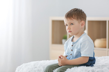 Fototapeta premium Little boy with autistic disorder sitting on bed at home