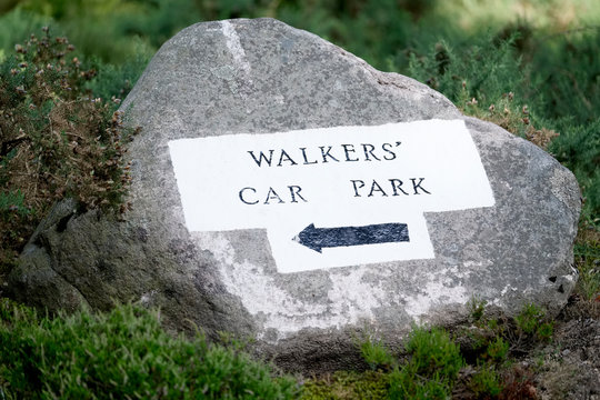 Walkers car park direction arrow sign painted on rock in woodlands