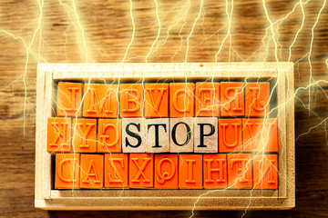 木目の上に置いたハンコ　STOP の文字と木目の背景と稲妻（雷）