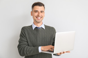 Handsome male teacher with laptop on white background