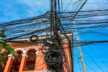 Huge messy tangle of dozens of electrical cables at the top of an electricity pole, Cambodia