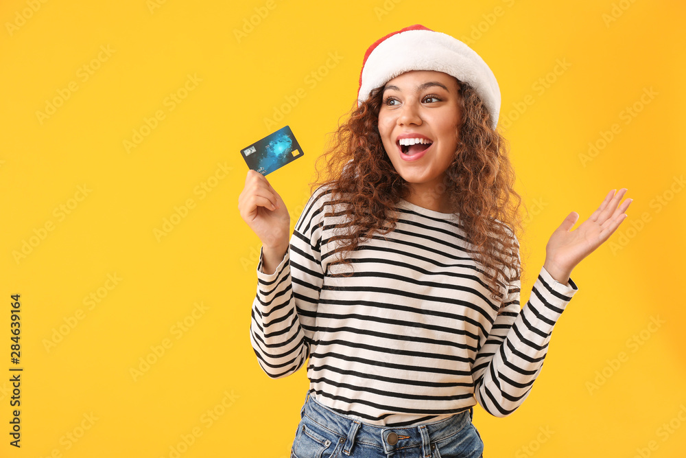 Canvas Prints Happy African-American woman in Santa hat and with credit card on color background